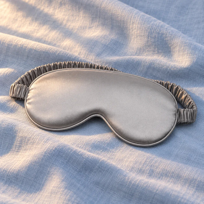 One grey satin-feel eye mask on styled blue linen